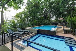 a swimming pool with a deck and two chairs next to it at Serenique Resort Kandy in Kandy