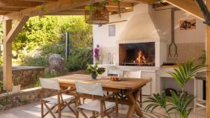 an outdoor kitchen with a wooden table and a fireplace at Casa Tramonto I Peaceful Family House with garden, Veli Lošinj in Veli Lošinj