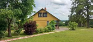 a yellow house in a yard with trees and grass at Kļūda 3 in Biksinīki