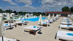 a row of lounge chairs with umbrellas next to a swimming pool at Grand Hotel Residence Pieštany Adult only Boutique hotel Next to Wake Soul Beach in Piešťany