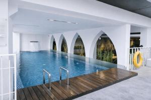 a swimming pool in a building with a wooden floor at Akmani Hotel Jakarta in Jakarta