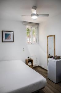 a white bedroom with a bed and a ceiling fan at Rooms Sincelejo in Madrid
