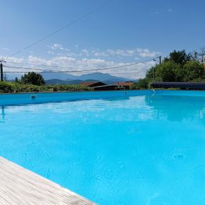 a large blue swimming pool with mountains in the background at Pyrenees Vue Gite Hoopoe - Le Plus Commentaires Positifs,Vues Fantastique, Petit-Déjeuner, Calme, Piscine, Parking in Saint-Gaudens