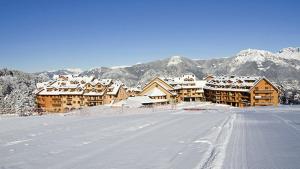 a snow covered road in front of a lodge at La Splaza Home in Pian Camuno