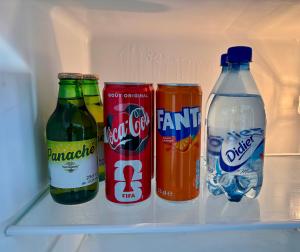 a refrigerator filled with drinks and soda bottles at Duplex cosy au cœur de Sinnamary, fleuve à pied- Samélé House in Sinnamary