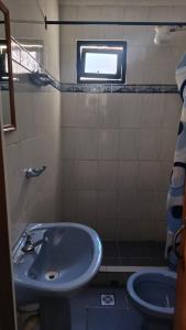 a bathroom with a sink and a toilet and a window at Hostal Churuquella in Sucre