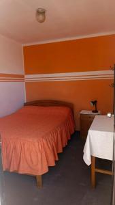 a bedroom with an orange bed and a table at Hostal Churuquella in Sucre