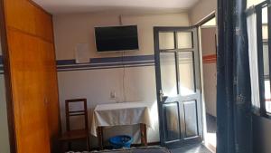 a room with a tv on the wall and a table at Hostal Churuquella in Sucre