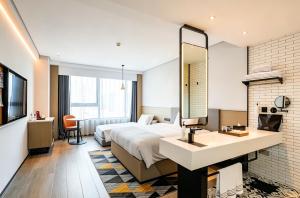 a hotel room with a bed and a sink and a mirror at Ningbo Wanda Moments Hotel in Ningbo +42 photos