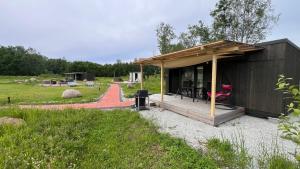 a small black house with a pink chair in a field at Mesipesa Holiday Houses in Narva-Jõesuu
