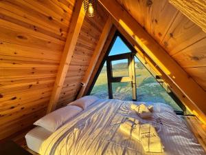 a bed in a wooden room with a window at Etno House Dragas in Njegovuđa