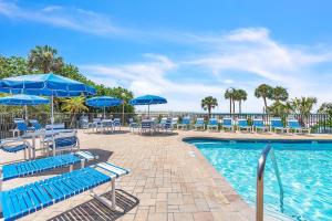 a swimming pool with blue chairs and umbrellas at Caprice 501 in St. Pete Beach