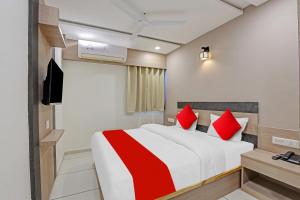 a hotel room with a bed with red pillows at Hotel O Max Inn in Ahmedabad