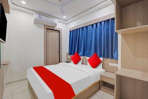 a bedroom with a bed with red pillows at Hotel O Max Inn in Ahmedabad +16 photos