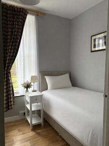 a bedroom with a white bed and a window at Castleroddy House - spacious country house - king beds - extensive parking in Lislap