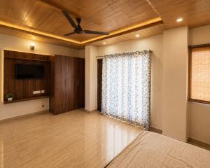 a living room with a ceiling fan and a television at Dharvi Kasauli Heavens in Kasauli