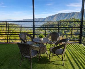 a table and chairs on a balcony with a view at Dharvi Kasauli Heavens in Kasauli