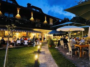 a group of people sitting at tables and umbrellas at Seehof Feidig in Velden am Wörthersee