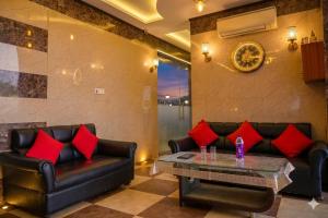 a living room with black leather furniture and red pillows at Jaipur Grand Bella in Jaipur