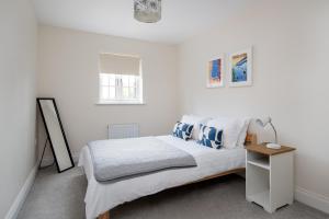 a white bedroom with a bed and a lamp at Finest Retreats - Field View in Brackley