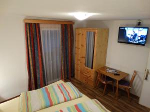 a bedroom with a bed and a table and a television at Gästehaus Posch in Krimml