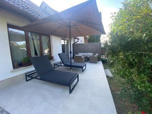 two chairs and an umbrella on a patio at Erelia Cottage in Bük