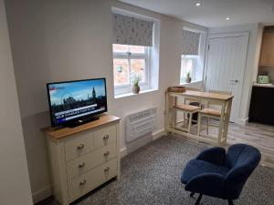 a living room with a television on a dresser and a chair at Sleeps2-CentralLocation-FamilyFriendly-NewRefurb in Retford