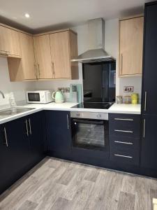 a kitchen with dark blue cabinets and white appliances at Sleeps2-CentralLocation-FamilyFriendly-NewRefurb in Retford