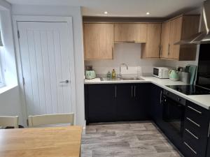 a kitchen with wooden cabinets and a sink at Sleeps2-CentralLocation-FamilyFriendly-NewRefurb in Retford
