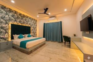 a bedroom with a bed and a desk and a television at Hotel Aura in Bikaner