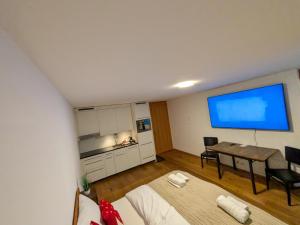 a room with a bed and a table and a blue screen at PlanB Stay in Silvaplana