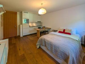 a bedroom with a large bed and a kitchen at PlanB Stay in Silvaplana