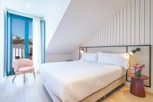 a bedroom with a large bed and a pink chair at Hotel Estepona Patio in Estepona