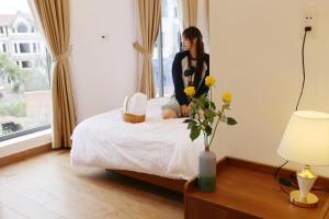 a woman sitting on a bed in a room at Enjoy Villa Da Lat in Khu Chi Lăng