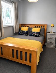 a bedroom with a large wooden bed with a yellow blanket at Seashells - Chalet 25 in Greatstone