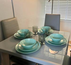 a table with four plates and glasses on it at Seashells - Chalet 25 in Greatstone