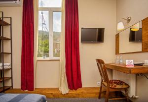 a bedroom with red curtains and a desk and a window at Hotel Beli in Tbilisi City +43 photos