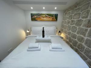 a bedroom with a white bed with a wine bottle on it at StonSoldo Rooms in Ston