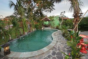 una piscina en un jardín con cenador en RedDoorz near Stadion Kompyang Sujana Bali en Denpasar