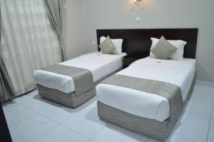 two beds in a hotel room with white floors at شقق أجنحة نزيل للشقق المخدومة in Tabuk