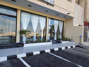 a building with windows with white curtains in a parking lot at شقق أجنحة نزيل للشقق المخدومة in Tabuk