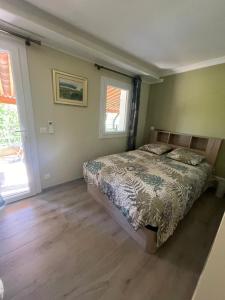 a bedroom with a bed and two windows at La Bernarde in Tourrettes