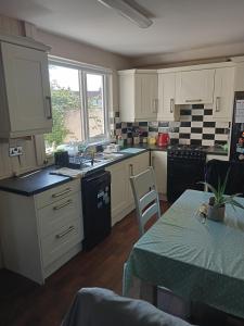 a kitchen with white cabinets and a table with a green tablecloth at Cozy stay in Dublin