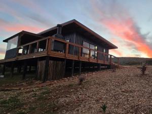 a wooden house on a hill with a sunset at Renosterveld Eco Pods in Swellendam
