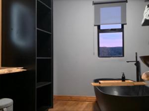 a bathroom with a black tub and a window at Renosterveld Eco Pods in Swellendam