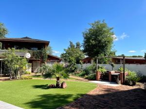 a house with a lawn with a palm tree in the yard at Cosy City Cottage in Gaborone