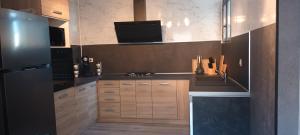a kitchen with wooden cabinets and a black refrigerator at Gîte Le Citronnier - Piscine partagée in Lagorce
