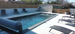a swimming pool with chairs in a backyard at Gîte Le Citronnier - Piscine partagée in Lagorce