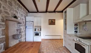 a kitchen with white appliances and a stone wall at Apartment Dyonis Perast in Perast