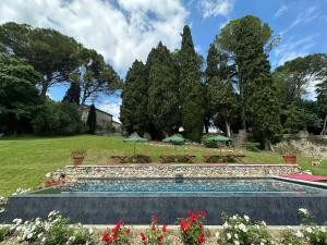 a swimming pool in a garden with tables and umbrellas at Villa Verecondi Scortecci in Colle Umberto